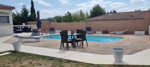 un patio avec une table et des chaises à côté d'une piscine dans l'établissement Dépendance 90m2 dans villa avec piscine, à Carcassonne