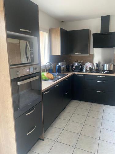 une cuisine avec des armoires noires et un four à plaques de cuisson dans l'établissement chambre spacieuse avec sauna, à Vern-sur-Seiche
