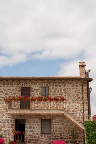 a stone building with red flowers on a balcony at Relais di campagna la polledrara in Paliano