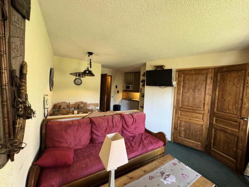 un salon avec un canapé rouge et une cuisine dans l'établissement Résidence Callisto - 2 Pièces pour 5 Personnes 90, à Mâcot La Plagne
