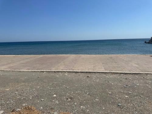 a brick walkway next to the ocean on a beach at Poppis Home in Ierápetra