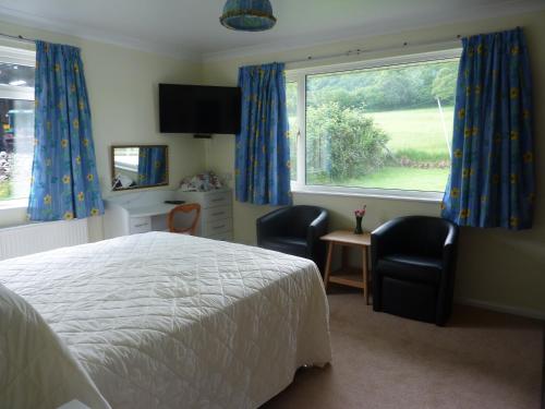 a bedroom with a bed and two chairs and a window at Snipelands Bed and Breakfast. in Flax Bourton