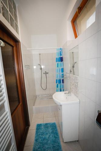 a white bathroom with a sink and a shower at Penzion SUNGARDEN-Veľký Meder in Veľký Meder