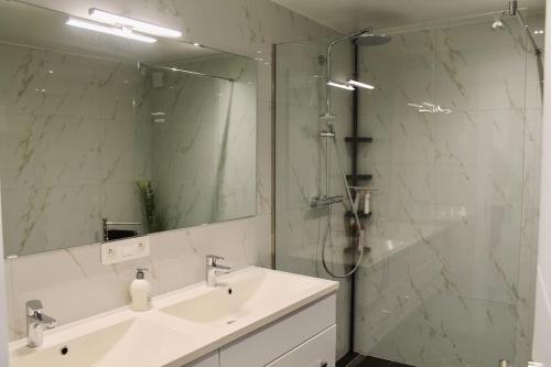 a bathroom with a sink and a shower with a mirror at Haus Wölmen in Heppenbach