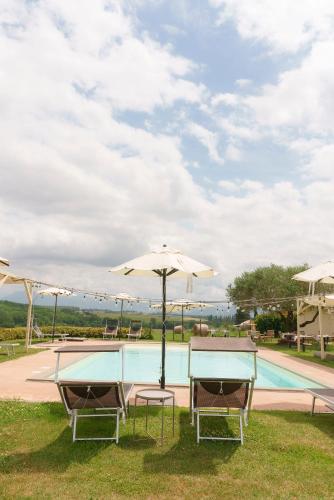 two chairs and an umbrella next to a swimming pool at Relais di campagna la polledrara in Paliano