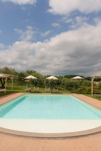 a large swimming pool with chairs and umbrellas at Relais di campagna la polledrara in Paliano