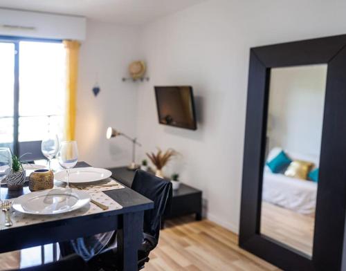 Una mesa de comedor con espejo y un dormitorio. en T2 Plage Prado-David, Parc Borély, Parking Privée, en Marsella
