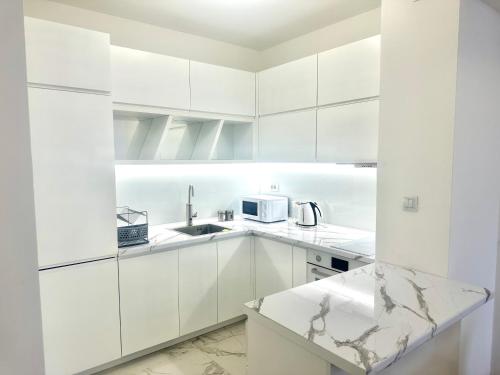 une cuisine blanche avec un évier et un micro-ondes dans l'établissement Skyline Oasis, à Skopje