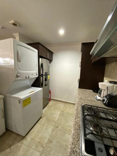 a kitchen with a white refrigerator and a stove at Departamento de Lujo, Cuenca, Adrianashome in Cuenca
