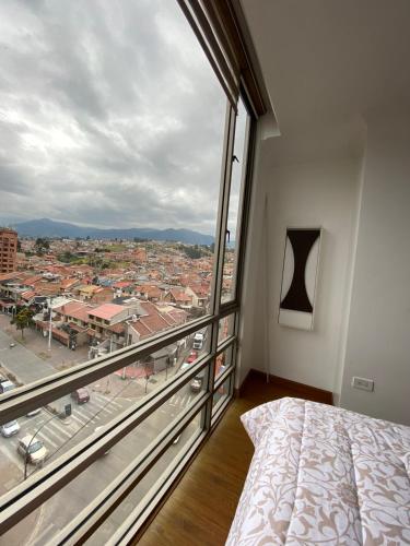 a bedroom with a large window with a view of a city at Departamento de Lujo, Cuenca, Adrianashome in Cuenca