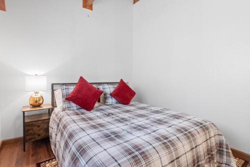 a bedroom with a bed with two red pillows on it at Cute Cozy Cabin - Nestled in the quiet neighborhood of Sugarloaf. in Sugarloaf