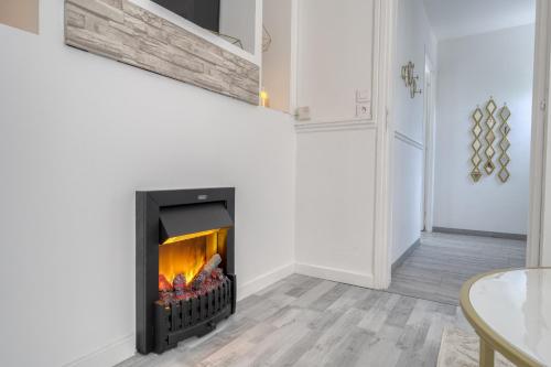 a fireplace in a living room with white walls at ZACH & SPA - Maison jardin à 20 min de Paris & Aéroport CDG in Livry-Gargan