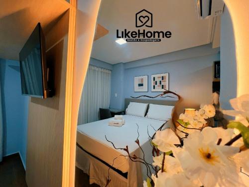 a hotel room with a bed and a tv and flowers at Edifício MOVE Novo- Tambaú in Tambaú