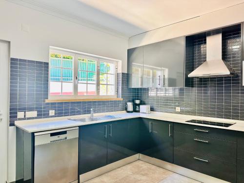une cuisine avec des armoires bleues et un évier dans l'établissement GLICINIAS Cascais Villa, à Birre