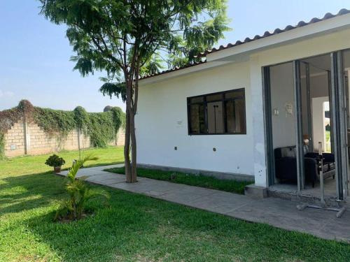 a white house with a tree in the yard at Fundo GHANDY ALLIZON in Larrea
