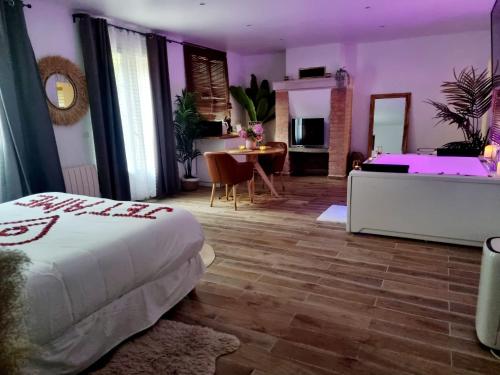 a bedroom with a bed and a table in a room at Suite de charme avec JACUZZI illimité et jardin privatif in Saint-Prix
