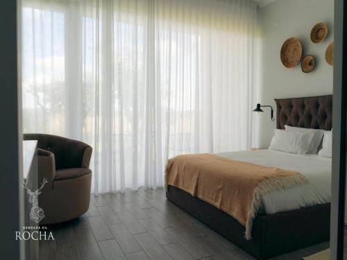 a bedroom with a bed and a chair next to a window at Herdade da Rocha - Boutique Lodge in Crato