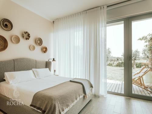 a bedroom with a bed and a sliding glass door at Herdade da Rocha - Boutique Lodge in Crato