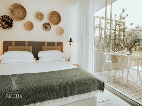 a white bedroom with a bed and a table at Herdade da Rocha - Boutique Lodge in Crato