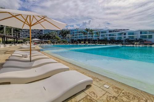 ヌエボ・バジャルタにあるDepartamento Frente al Mar Ariaの大きなスイミングプール(椅子、パラソル付)