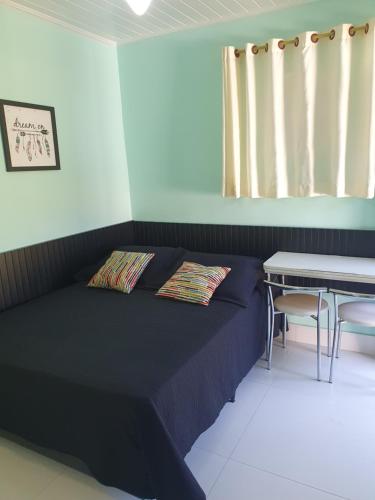 Schlafzimmer mit einem Bett und einem Tisch sowie einem Tisch und Stühlen in der Unterkunft Apartamento Bangalo Cabo Frio in Cabo Frio