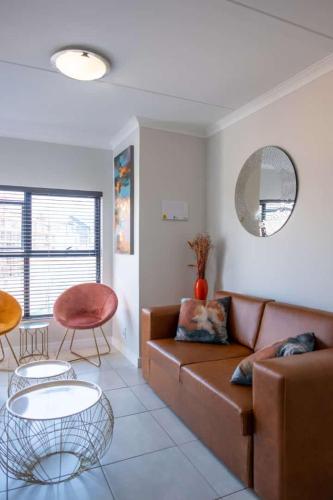 a living room with a brown couch and two tables at Unit 1310 The Blyde in Boschkop