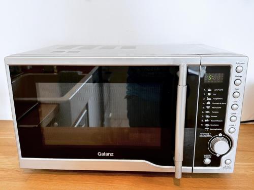 a microwave oven sitting on top of a table at Au Bon Accueil - Appartement vue mer - Hyper centre - Avec Home-Cinéma in Carantec