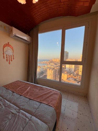 a bedroom with a bed and a large window at Nubian Village by the Sea in Alexandria