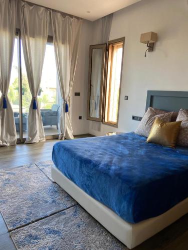 a bedroom with a large bed with blue sheets and windows at VILLA De LUXE in Marrakesh
