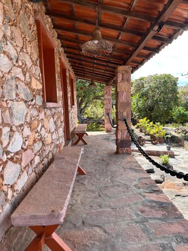 a stone building with a bench on a patio at Recanto Bela Vista Igatu in Igatu