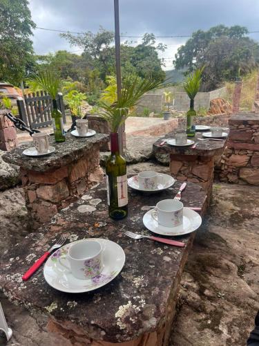 a table with plates and cups and a bottle of wine at Recanto Bela Vista Igatu in Igatu