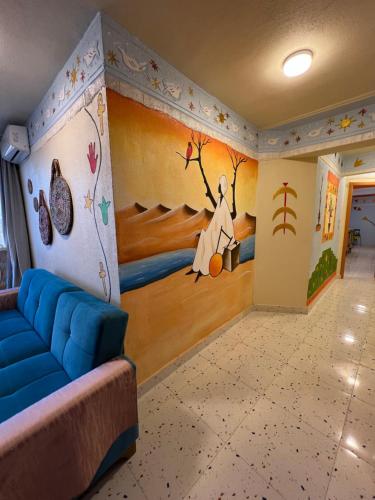 a living room with a blue couch in a room with a painting at Nubian Village by the Sea in Alexandria