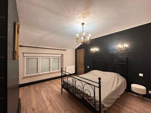 a black bedroom with a bed and a chandelier at Gîte OPLM 8 p Proximité Charleville in Prix-lès-Mézières