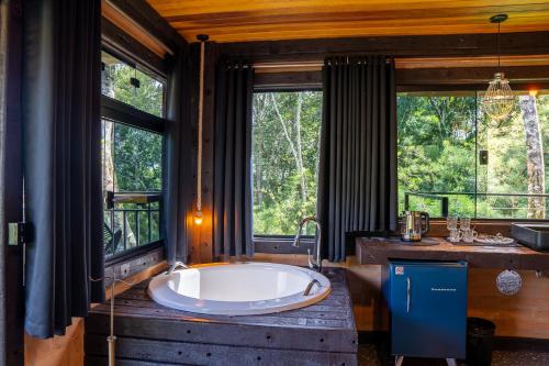 a large bath tub in a bathroom with windows at Casa Container 80 in Campos do Jordão