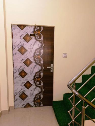 a door in a hallway with a green carpet and stairs at Grihalaxmi Paying Guest House in Varanasi