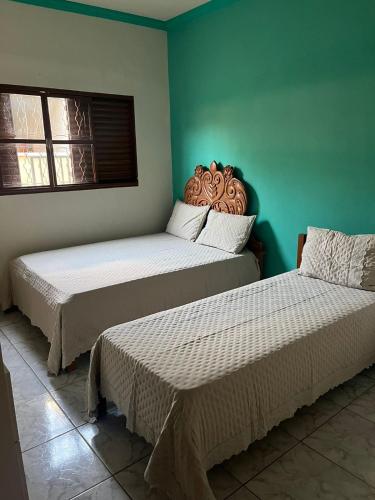 two beds in a room with green walls at Casa de Temporada Ipê Rosa in Bonito
