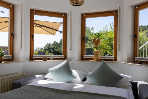 a bedroom with a bed with pillows and windows at Hambach Waldschlössl in Neustadt an der Weinstraße