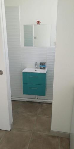 La salle de bains est pourvue d'une armoire bleue et d'un lavabo. dans l'établissement florensac, à Florensac
