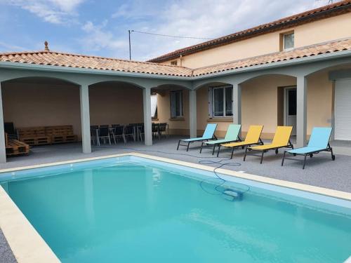 une piscine avec des chaises et une maison dans l'établissement Gîte de campagne 14 personnes, à Bégrolles-en-Mauges