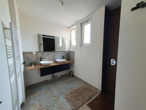 ein Badezimmer mit zwei Waschbecken und einem Spiegel in der Unterkunft Gîte de campagne 14 personnes in Bégrolles-en-Mauges