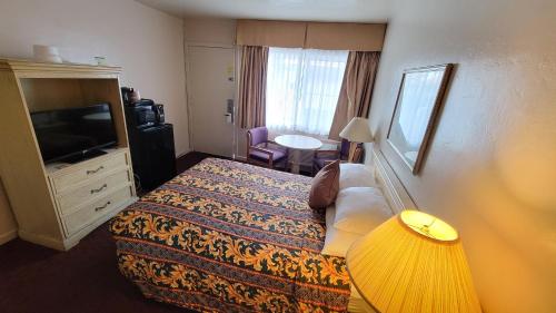 a hotel room with a bed and a television at El Camino Inn in Daly City