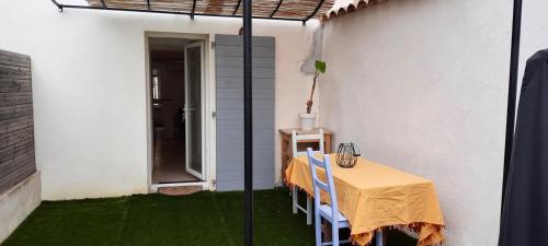 un patio avec une table et des chaises sur l'herbe dans l'établissement Charmant studio avec terrasse ombragée, à Six-Fours-les-Plages