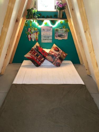 a bed with three pillows on it in a room at Tiny Beach Hut - Faith Bay Huts 3 in Camiing