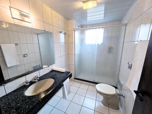 a bathroom with a sink and a toilet and a shower at Hotel Germânia in Joinville