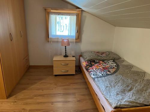 a small bedroom with a bed and a lamp on a night stand at Historische Maisonettewohnung bis 10 Gäste, Magic Pass Belalp, Rosswald und mehr in Naters