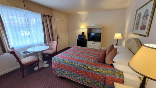 a hotel room with a bed and a table and a television at El Camino Inn in Daly City