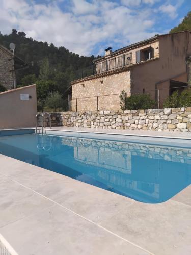 une piscine en face d'une maison avec un mur en pierre dans l'établissement 10 mn Buis les Baronnies, à Plaisians