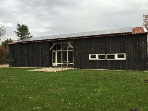 a black barn with windows and a grass field at Gastenverblijf Eindhoven in Eindhoven