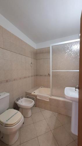 a bathroom with a toilet and a tub and a sink at Manantiales Hotel Boutique in Victoria