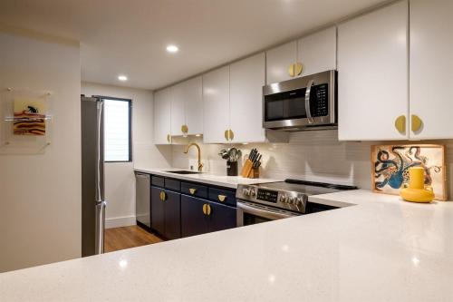 a kitchen with white cabinets and a counter top at Remodeled 3 Bedroom Oceanfront Condo — Sleeps 8 in Wailuku